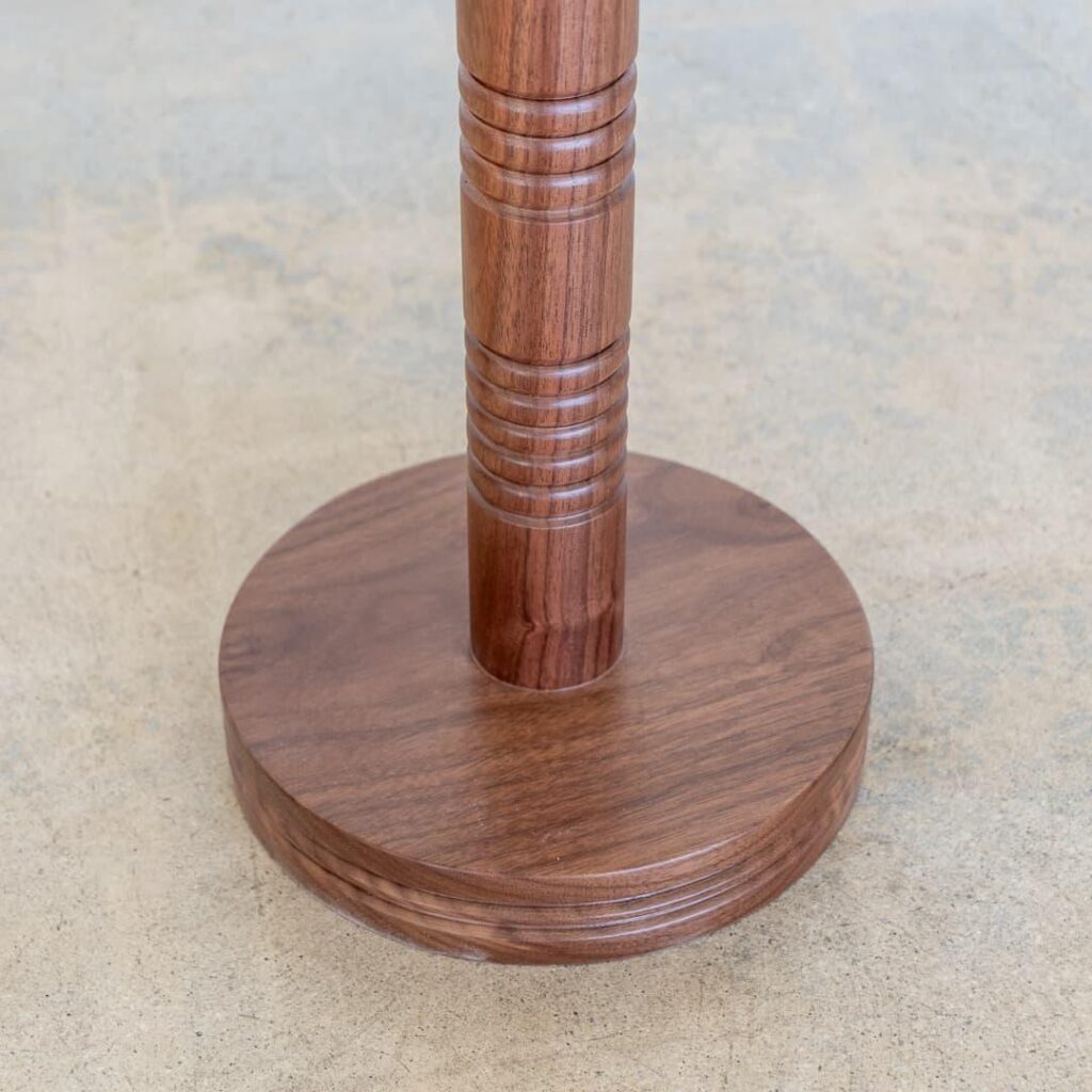 This elegant and versatile wooden drink table is a beautiful addition to any home or commercial space. The circular tabletop is crafted from high-quality walnut wood, showcasing its natural grain and warm tones. The unique, intricately carved ribbed detailing on the central support adds a touch of artistry and visual interest. This table is perfect for serving drinks, snacks, or displaying decorative items