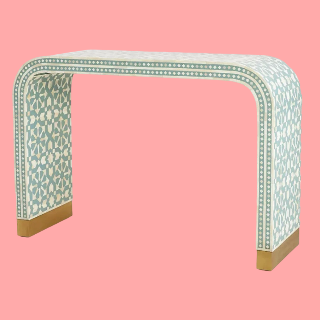 Bring a touch of elegance and craftsmanship to your living space with this exquisite Bone Inlay Console Table. Handcrafted by skilled artisans, this piece features intricate hand-carved bone details and curvaceous corners that create a sophisticated and timeless design. The console is made from solid wood and MDF for durability and longevity. Its base is accentuated with a brass cladding, offering a luxurious touch while enhancing the overall aesthetics. With its sleek and modern form, this console table is perfect for your entryway, living room, or hallway, adding both beauty and functionality to any space.